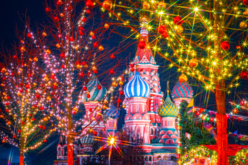 Christmas in Moscow. Decorated trees on the background of St. Basil Cathedral. New year in the capital of Russia. Holiday lights on the city street. Christmas greetings from Russia.