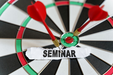 A piece of paper with the text is nailed to the target with a dart - SEMINAR