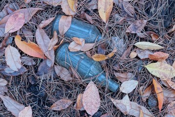 garbage from two gray glass bottles on brown dry vegetation on a nature