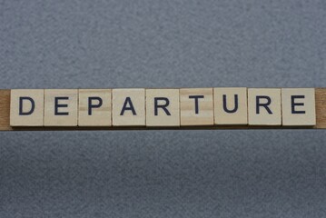 text the word departure from brown wooden small letters with black font on an gray table