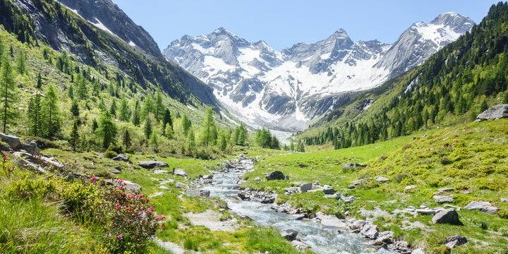 Panorama einer fantastischen idyllischen Alpenlandschaft mit Gebirgsfluß und einem Gletscher im Hintergrund