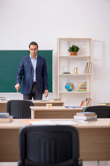 Young male teacher in front of green board