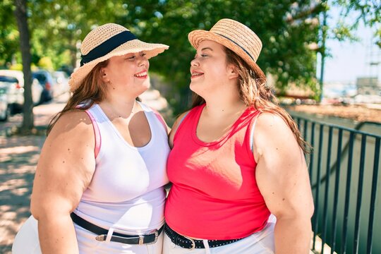 Two plus size overweight sisters twins women hugging together outdoors
