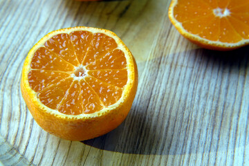 Tangerine sliced on a wooden board. White core, yellow-orange peel scin and juicy shiny glossy...