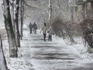 Fototapeta na wymiar 2016-11-13 Kyiv, Ukraine. Pedestrians on the slippery road during heavy snowfall.