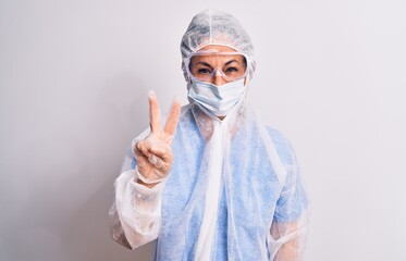 Middle age nurse woman wearing protection coronavirus equipment over white background showing and pointing up with fingers number two while smiling confident and happy.
