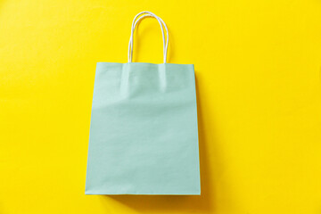 Simply minimal design shopping bag isolated on yellow background. Online or mall shopping shopaholic concept. Black friday Christmas season sale. Flat lay top view copy space, mock up