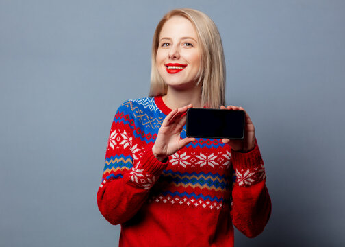 Beautiful blonde in Christmas sweater with mobile phone