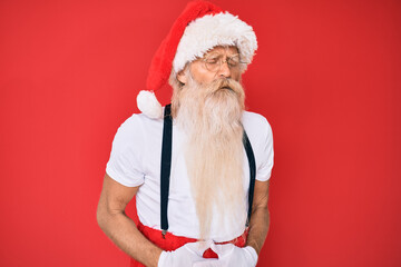 Old senior man with grey hair and long beard wearing white t-shirt and santa claus costume with hand on stomach because indigestion, painful illness feeling unwell. ache concept.