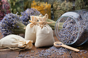 Glass jar of dry lavender flowers, sachets, bunches of dry lavender. Jars of different dry...