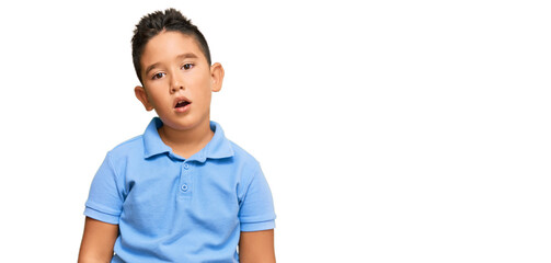 Little boy hispanic kid wearing casual clothes in shock face, looking skeptical and sarcastic, surprised with open mouth