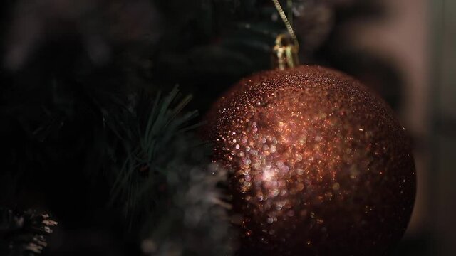 Christmas live background. New Year's toy. Macro shooting. New Year's brown ball dangles on a Christmas tree branch. Christmas decoration on the Christmas tree