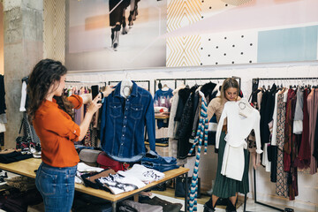 Beautiful young women trying elegant clothes in expensive boutique or store.