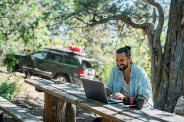 Male photographer working on a laptop outdoors in a camping