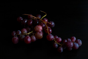 Red grapes, large bunch of fruits, fresh and tasty simple food on a dark background in a fancy minimal composition