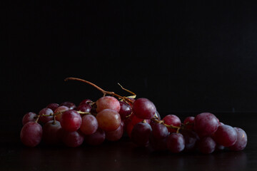 Red grapes, large bunch of fruits, fresh and tasty simple food on a dark background in a fancy minimal composition