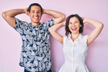 Beautiful couple wearing casual clothes relaxing and stretching, arms and hands behind head and neck smiling happy