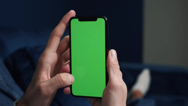 Close up man holding in arms electronics gadget with greenscreen touchpad, scrolling and tapping.