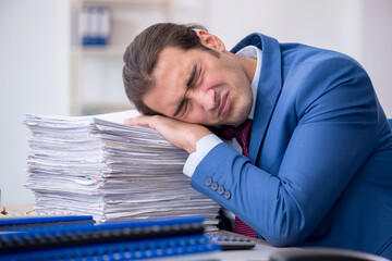 Obraz premium Young male employee unhappy with excessive work in the office
