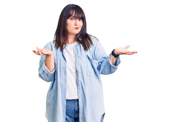 Young plus size woman wearing casual clothes clueless and confused expression with arms and hands...