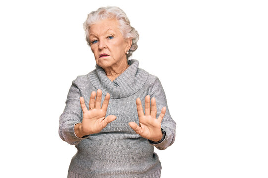 Senior grey-haired woman wearing casual winter sweater moving away hands palms showing refusal and denial with afraid and disgusting expression. stop and forbidden.