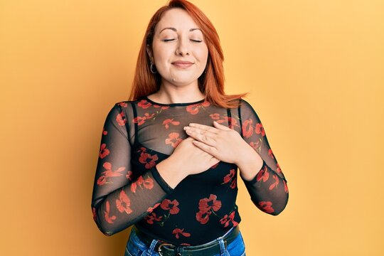 Beautiful redhead woman wearing casual clothes smiling with hands on chest, eyes closed with grateful gesture on face. health concept.