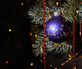 A blue glass ball on a Christmas tree. Dark background.