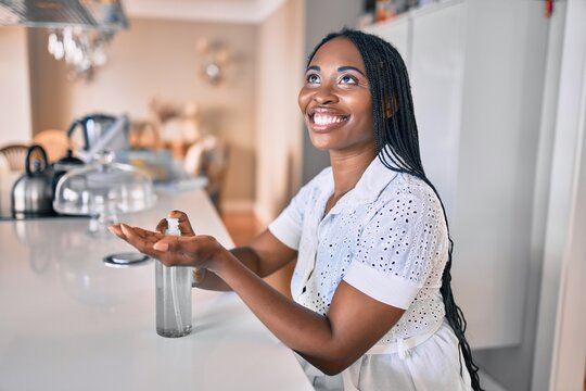 Young african american woman smiling happy using sanitizer hand gel at home