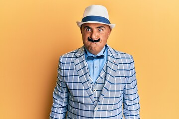 Mature middle east man with mustache wearing vintage and elegant fashion style puffing cheeks with funny face. mouth inflated with air, crazy expression.
