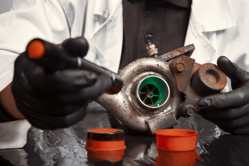 Man checking and measuring carbonized turbocharger on table