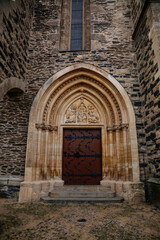 Fototapeta na wymiar Gothic portal of medieval stone St. Bartholomew´s Church, architectural element of facade, decorative bas-relief details, Gothic Cathedral in Kolin, Central Bohemia, Czech republic