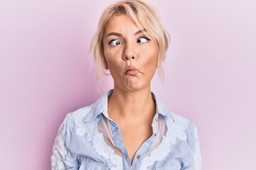 Young blonde girl wearing casual clothes making fish face with lips, crazy and comical gesture. funny expression.