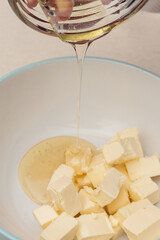 Pieces of butter are poured with honey in a bowl. Close-up shot. Selective focus.