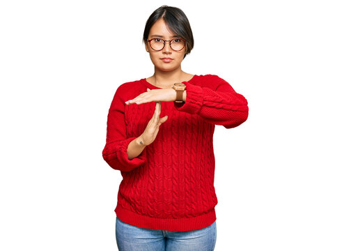 Young beautiful hispanic woman with short hair wearing casual sweater and glasses doing time out gesture with hands, frustrated and serious face
