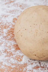 Gingerbread dough ball lies on flour covered table.