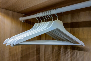Rack with clothes hangers in a brown wardrobe.