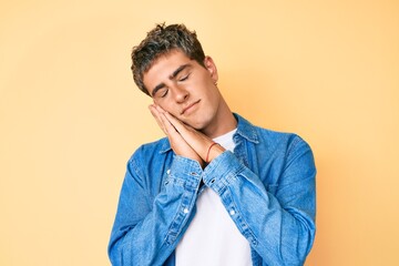 Young handsome man wearing casual clothes sleeping tired dreaming and posing with hands together while smiling with closed eyes.