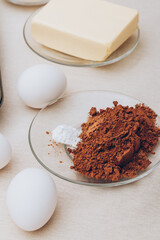 Ingredients for cooking. Eggs, cacao and piece of butter on tablecloth.