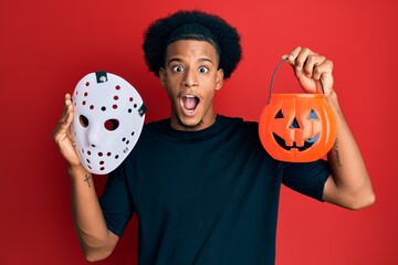 African american man with afro hair wearing hockey mask and halloween pumpking celebrating crazy and amazed for success with open eyes screaming excited.