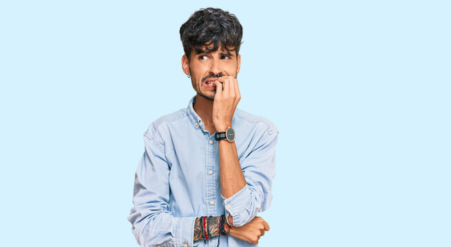 Young hispanic man wearing casual clothes looking stressed and nervous with hands on mouth biting nails. anxiety problem.