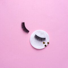 Creative concept beauty fashion photo of lashes extensions brush on pink background.