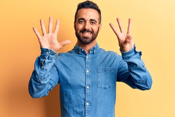 Fototapeta premium Young hispanic man wearing casual clothes showing and pointing up with fingers number eight while smiling confident and happy.
