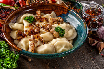 Pierogi or pyrohy, varenyky, vareniki, dumplings served with caramelized salted onion in bowl on wooden table - traditional Ukrainian food