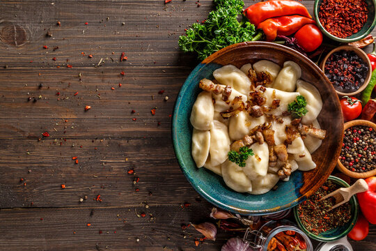 Pierogi or pyrohy, varenyky, vareniki, dumplings served with caramelized salted onion in bowl on wooden table - traditional Ukrainian food