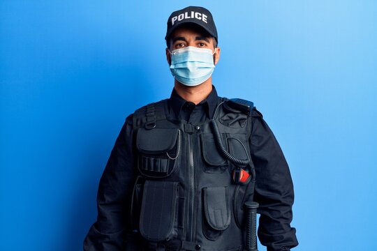 Young hispanic man wearing police uniform and medical mask with a happy and cool smile on face. lucky person.
