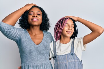 Beautiful african american mother and daughter wearing casual clothes and hugging smiling confident touching hair with hand up gesture, posing attractive and fashionable