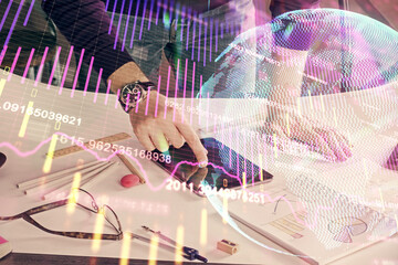 Double exposure of man's hands holding and using a digital device and forex graph drawing. Financial market concept.