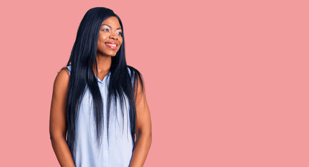 Young african american woman wearing casual clothes looking away to side with smile on face, natural expression. laughing confident.