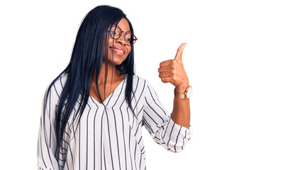 Young african american woman wearing casual clothes and glasses looking proud, smiling doing thumbs up gesture to the side