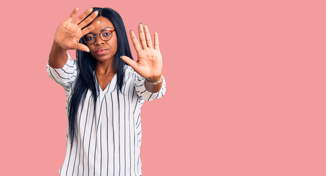 Young african american woman wearing casual clothes and glasses doing frame using hands palms and fingers, camera perspective